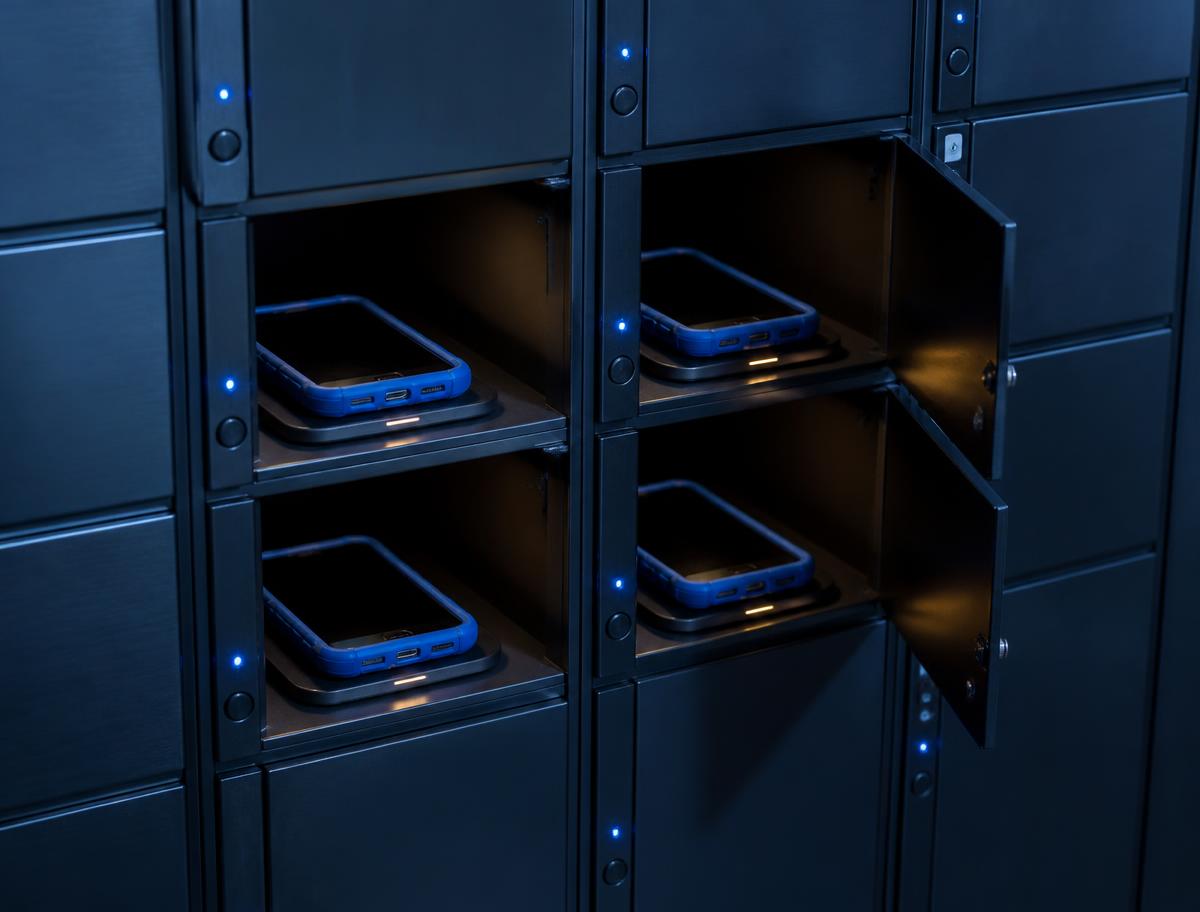 Bank of compact smart lockers with indicator lights and identical bright blue-cased camera devices charging in open bays